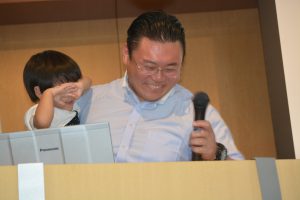 我慢できずに壇上に上がってきたお子さんを抱っこしながらの本日のまとめ（＊お子さんは、中島委員長のお子さんでのありません。）